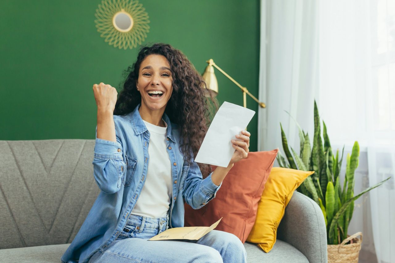 portrait of happy woman at home hispanic woman smiling and looking at camera holding envelope with